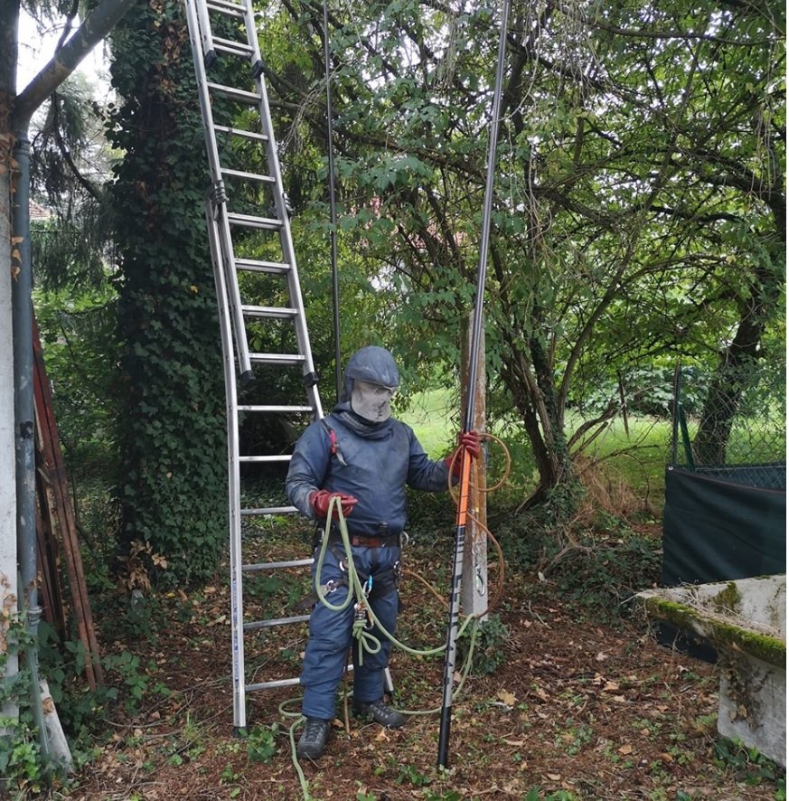 Technicien en combinaison avec echelle et perche telescopique